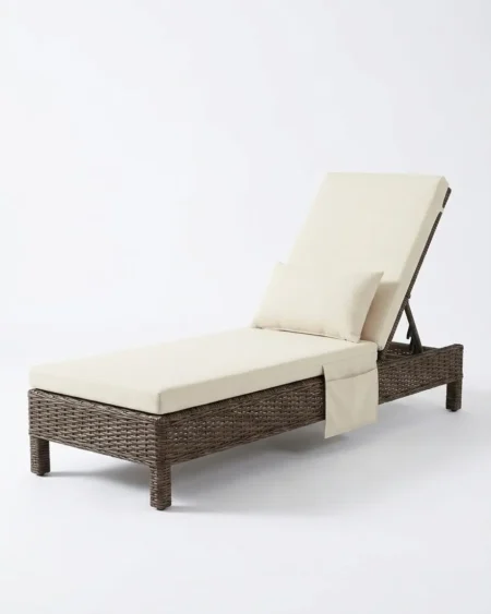 Luxury Bramwell wicker sun lounger featuring a rust-proof aluminium frame, an integrated side pocket, and UV-stabilized brown synthetic rattan, manufactured for high-end resorts.