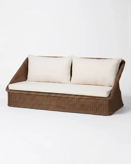 The Cognac Slant Back Rattan Sofa featuring a sophisticated 2-seater design with a braided edge natural rattan weave and cream cushions.