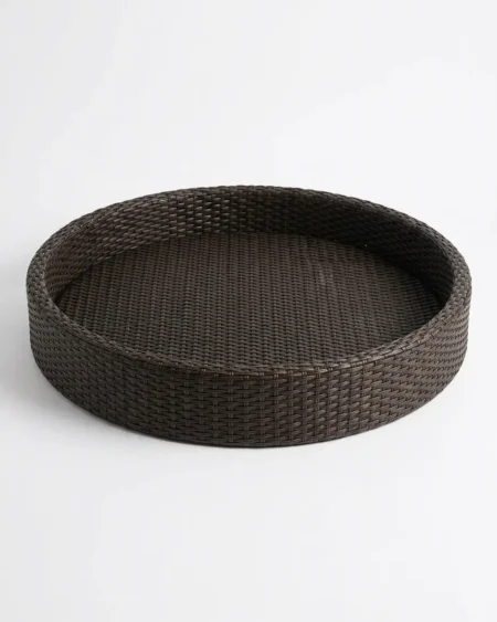 The Onyx Round Weave Low Tray featuring a sleek dark rattan finish over a rust-proof aluminum core.