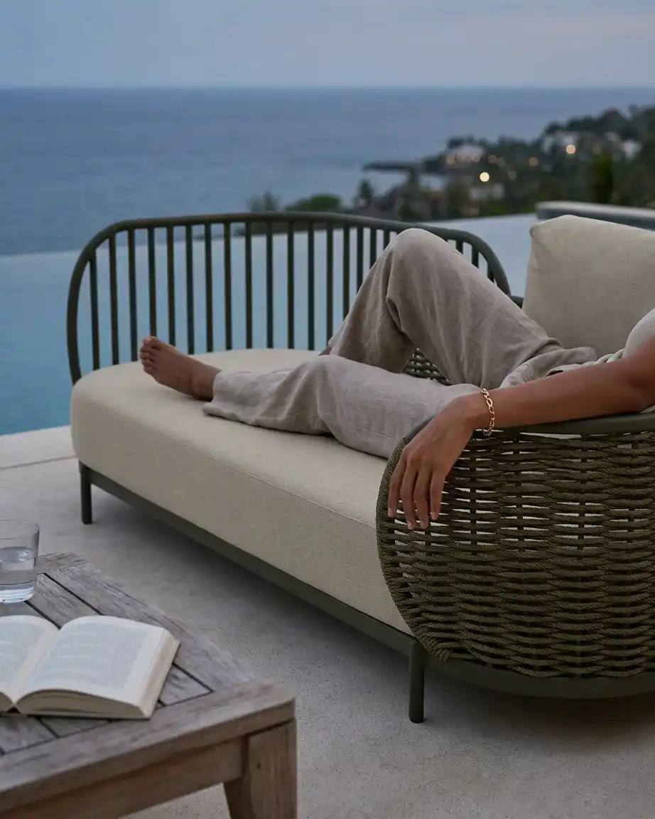 Side profile of the armless daybed sofa highlighting the intricate vertical rope slat weave and high-density waterproof olive green cushions.