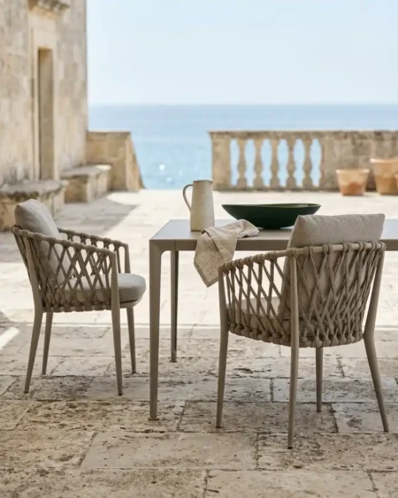 Luxury taupe marine-grade aluminium Taormina criss-cross rope armchair with UV-stabilized cord and backrest pillow for commercial outdoor dining sets.